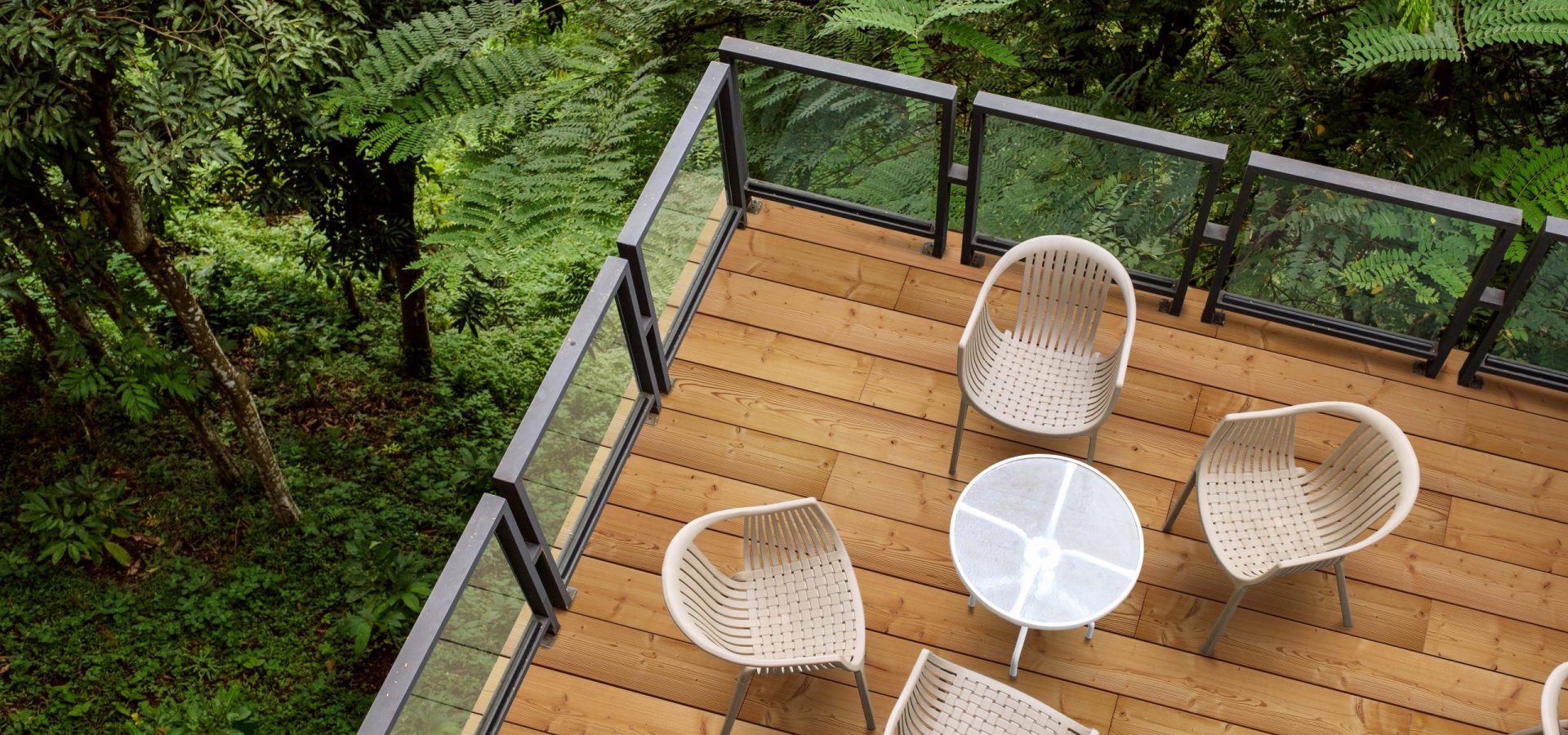 Wooden chairs with glass table on patio in tropical garden